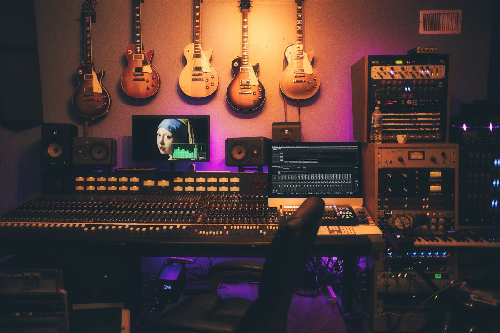 Dark control room with mixing console and monitors